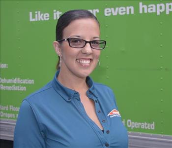 Female employee wearing glasses with teal SERVPRO® shirt in front of SERVPRO truck