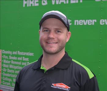 Male employee earing a green and black SERVPRO shirt and a gray and black SERVPRO hat