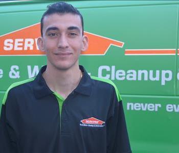Male employee with black and green SERVPRO shirt with a green background.